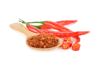 ground chili in wooden spoon and fresh red chili with stem on white background