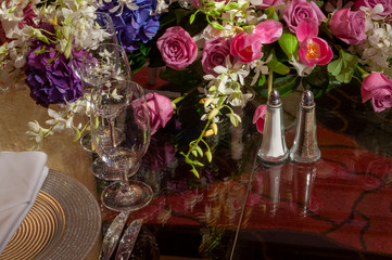 Salt and pepper shakers with fine dinnerware on glass banquet table