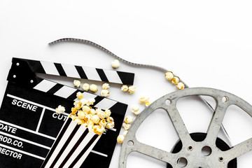 Watch film in cinema with popcorn, video tape and clapperboard on white background top view