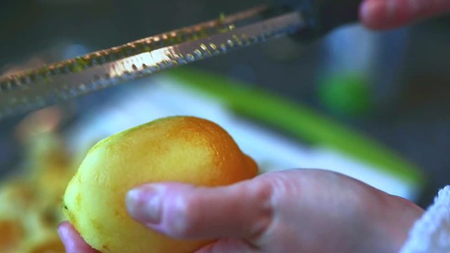 Female home cook zesting a freshly picked organic lemon in the kitchen.