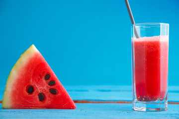 a piece of watermelon and smoothie,freshly squeezed watermelon juice in a transparent glass on a...