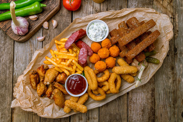 assorted beer snacks on the board with sauses on wooden table
