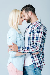 beautiful young couple hugging and looking at each other isolated on grey