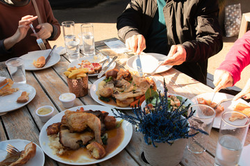 Group of family and friends share foods and having lunch time outdoor together on wooden table in sunny day