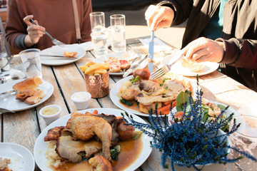 Group of family and friends share foods and having lunch time outdoor together on wooden table in sunny day