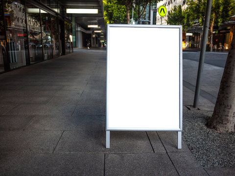 Blank white outdoor advertising stand/sandwich board mock up template. Background texture of clear street signage board placed outdoor on pedestrian sidewalk. Urban city environment.