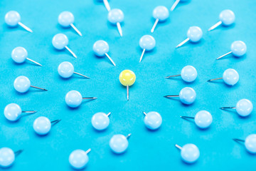 blue paper clips around one yellow paper clip on blue background, violence concept