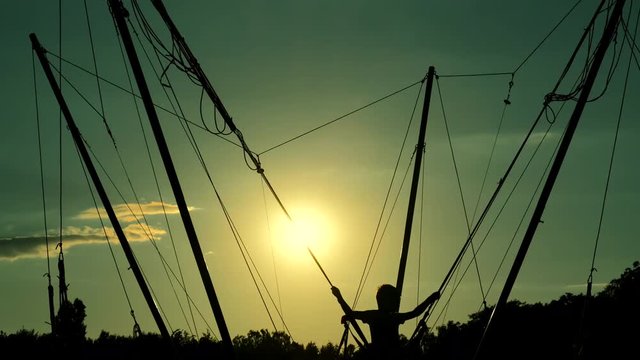 Silhouettes at sunset. Children jump on a trampoline Kangaroo. Recreation, entertainment and sports activity. Equipment used for jumping, playing and having fun. trampoline jumping rope