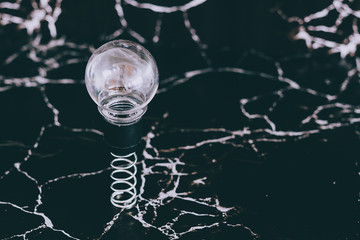 idea lightbulb popping up on spring with black marble background