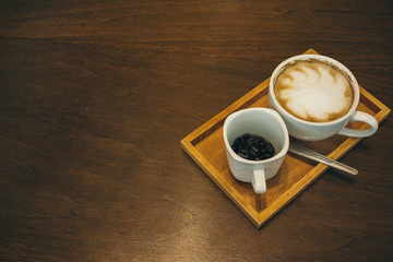Coffee cup and coffee beans on wooden table  in cafe