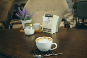 Coffee cup and coffee beans on wooden table  in cafe