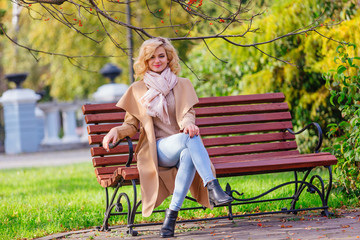 Young beautiful woman sitting on the bench in autumn park