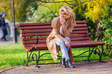 Young beautiful woman sitting on the bench in autumn park