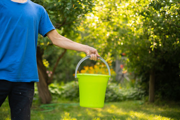 holding a color plastic bucket with pure water