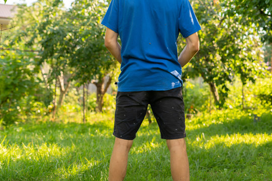rear view of young person standing outdoor and piss under the tree