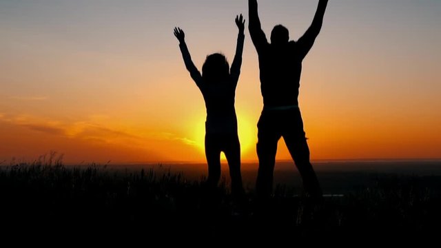 back woman and man have fun standing on the hill or mountain happiness and joy silhouette couple at sunset