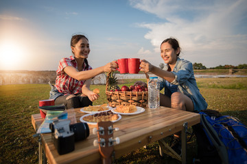 A group of Asian friends drinking coffee and spending time making a picnic in the summer holidays.They are happy and have fun on holidays.