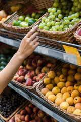 cropped view of woman gesturing near fruits in supermarket