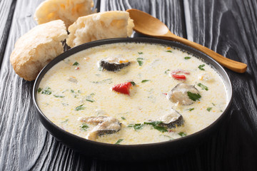 Portion of creamy fish soup with eel, vegetables and herbs close-up on the table. horizontal