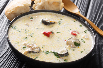 Hearty creamy fish soup with eel, vegetables and herbs close-up in a bowl. horizontal