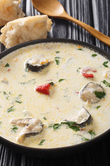 Cream soup puree with eel fish, cheese and vegetables closeup in a bowl. vertical