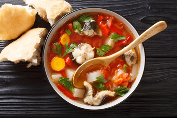 Eel soup with tomatoes, potatoes, carrots, onions, peppers and herbs closeup in a bowl. horizontal top view
