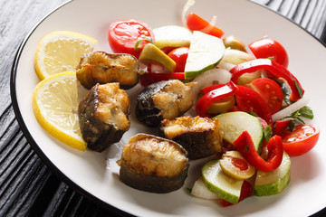 Gourmet food fried eel with fresh vegetable salad close-up on a plate. vertical