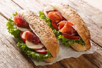 Snack sandwiches with jamon, mozzarella cheese, tomatoes and leaf salad close-up. horizontal