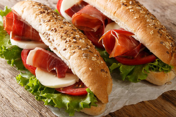 Mediterranean sandwiches with jamon, mozzarella cheese, tomatoes and leaf lettuce close-up on the...