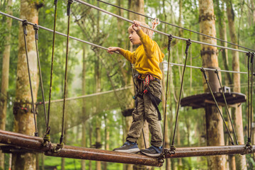 Little boy in a rope park. Active physical recreation of the child in the fresh air in the park. Training for children