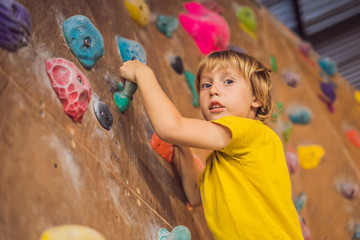 little boy climbing a rock wall in special boots. indoor