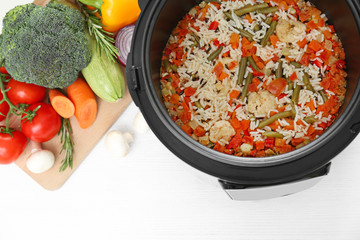 Prepared rice with vegetables in multi cooker on kitchen table, above view