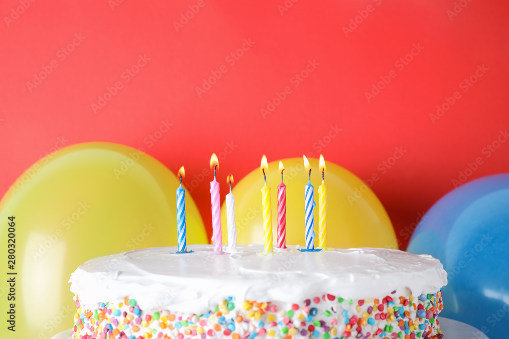 Wall mural Tasty birthday cake with burning candles and balloons on red background, space for text