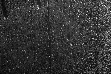Glass with rain drops against dark background
