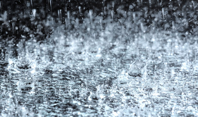 Plakat Heavy rain falling down on ground against dark background