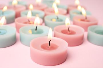 Obraz na płótnie Canvas Burning colorful decorative candles on pink background, space for text
