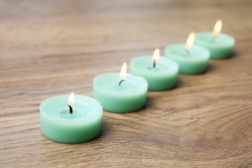 Obraz na płótnie Canvas Burning turquoise decorative candles on wooden table