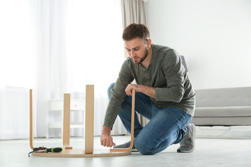 Young working man repairing table at home