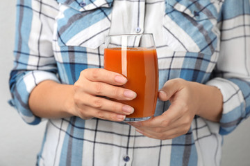 Woman holding glass of tasty carrot juice, closeup