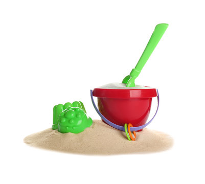 Set of plastic beach toys and pile of sand on white background