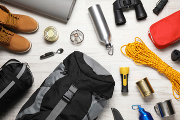Flat lay composition with different camping equipment on wooden background