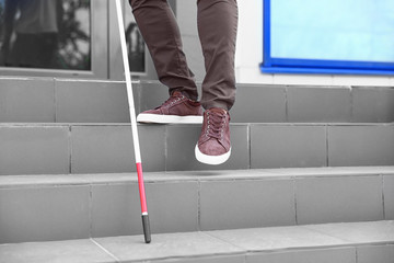Blind person with cane going down stairs outdoors, closeup