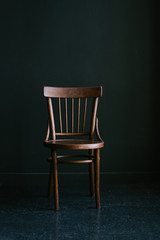 Old-fashioned wooden chair on a dark background in the interior - obrazy, fototapety, plakaty