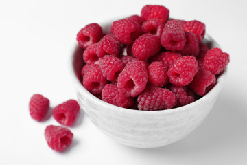Bowl of delicious ripe raspberries on white background