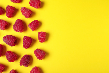 Flat lay composition with delicious ripe raspberries on yellow background. Space for text