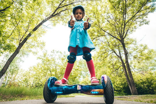 Girl rides on a modern board of self-balancing with a cat in forest in a summer park. Active lifestyle. Electric scooter. Hover-board. New self-balancing board. Gyro scooter