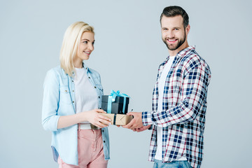 smiling man giving presents to beautiful girl isolated on grey