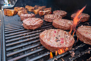 close up of hamburgers and lamb chops on a gas outdoor grill