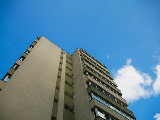 Reconditioned old apartment building against blue sky with white clouds in Romania.