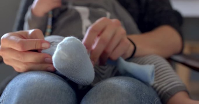Mother putting socks on baby feet having fun